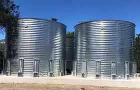 Two corrugated steel tanks side by side on a concrete foundation
